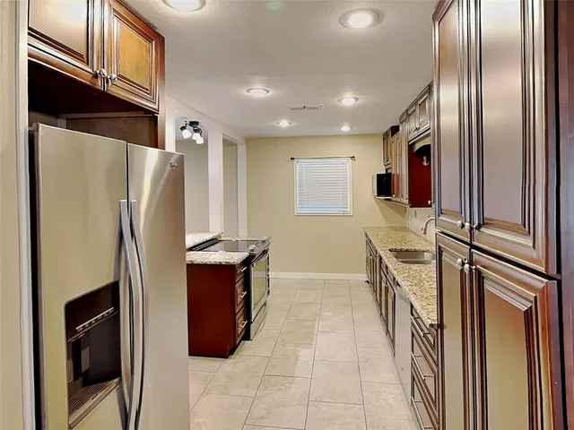 a kitchen with stainless steel appliances granite countertop a refrigerator a stove and a refrigerator