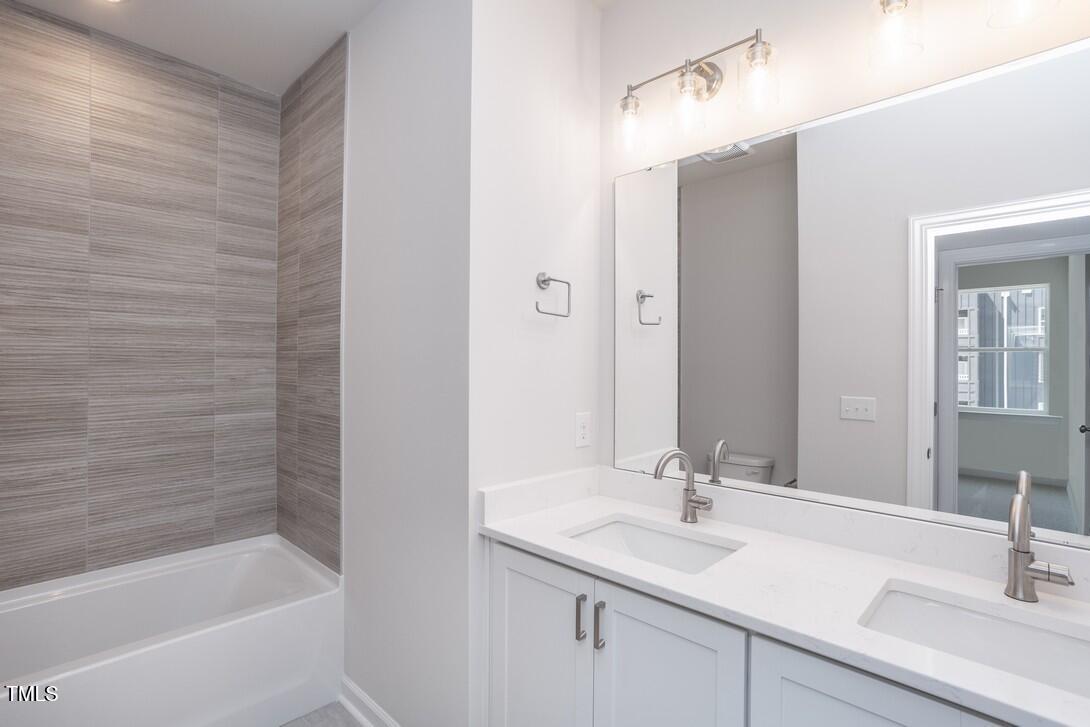 4703 Mint Leaf Lane Raleigh, NC 27612 - Photo 19 of 25 a bathroom with a granite countertop sink a mirror and a bathtub