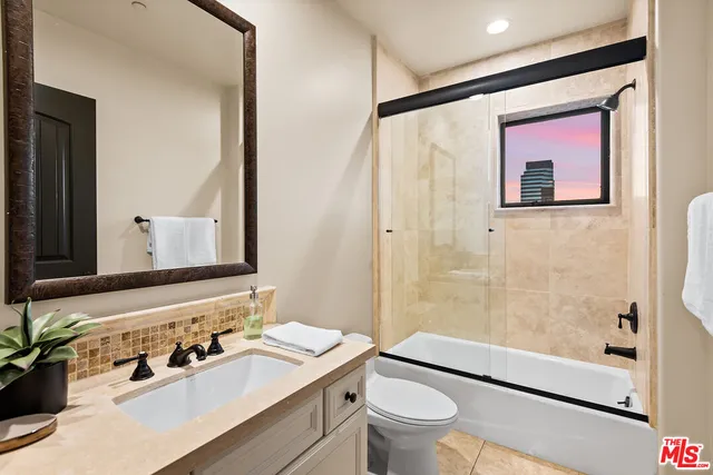 a bathroom with a sink a toilet a mirror and shower