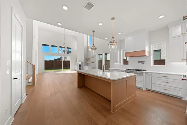 a large kitchen with stainless steel appliances a stove a sink dishwasher and a refrigerator with wooden floor