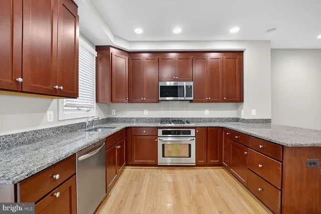 a kitchen with stainless steel appliances granite countertop wooden cabinets and a stove top oven