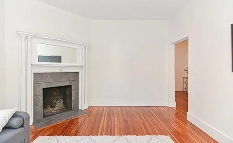 a view of a livingroom with wooden floor and a fireplace