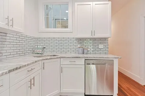 a kitchen with white cabinets and sink