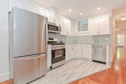 a kitchen with white cabinets white stainless steel appliances and wooden floors