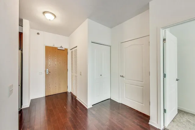a view of an empty room with wooden floor and entryway