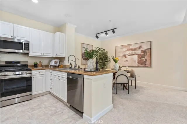 a kitchen with stainless steel appliances granite countertop a stove a sink dishwasher and a microwave oven with white cabinets