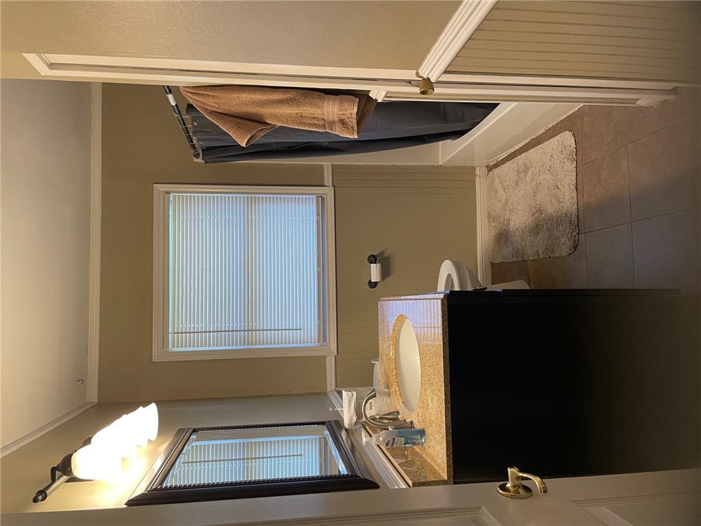 4400 Oaklawn Street Bryan, TX 77801 - Photo 4 of 7 a bathroom with a sink a toilet and mirror