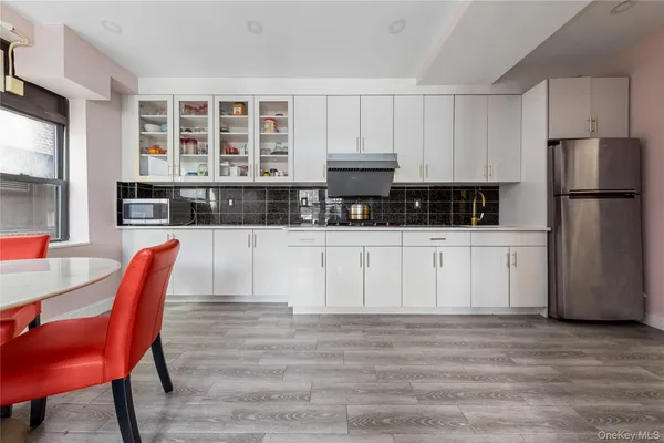 a kitchen with stainless steel appliances granite countertop a stove a refrigerator a dining table and chairs