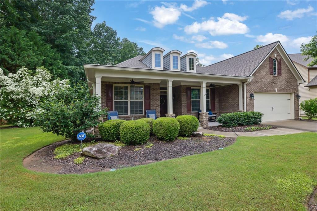 a view of a brick house with a yard plants and large tree