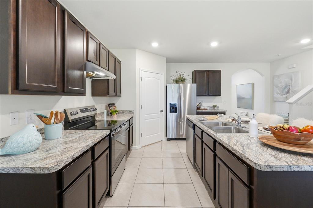 416 Corso Loop Winter Haven, FL 33884 - Photo 13 of 73 a kitchen with granite countertop kitchen island stainless steel appliances a sink stove top oven and refrigerator