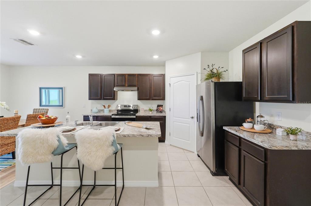416 Corso Loop Winter Haven, FL 33884 - Photo 15 of 73 a kitchen with stainless steel appliances kitchen island granite countertop a refrigerator and a stove top oven