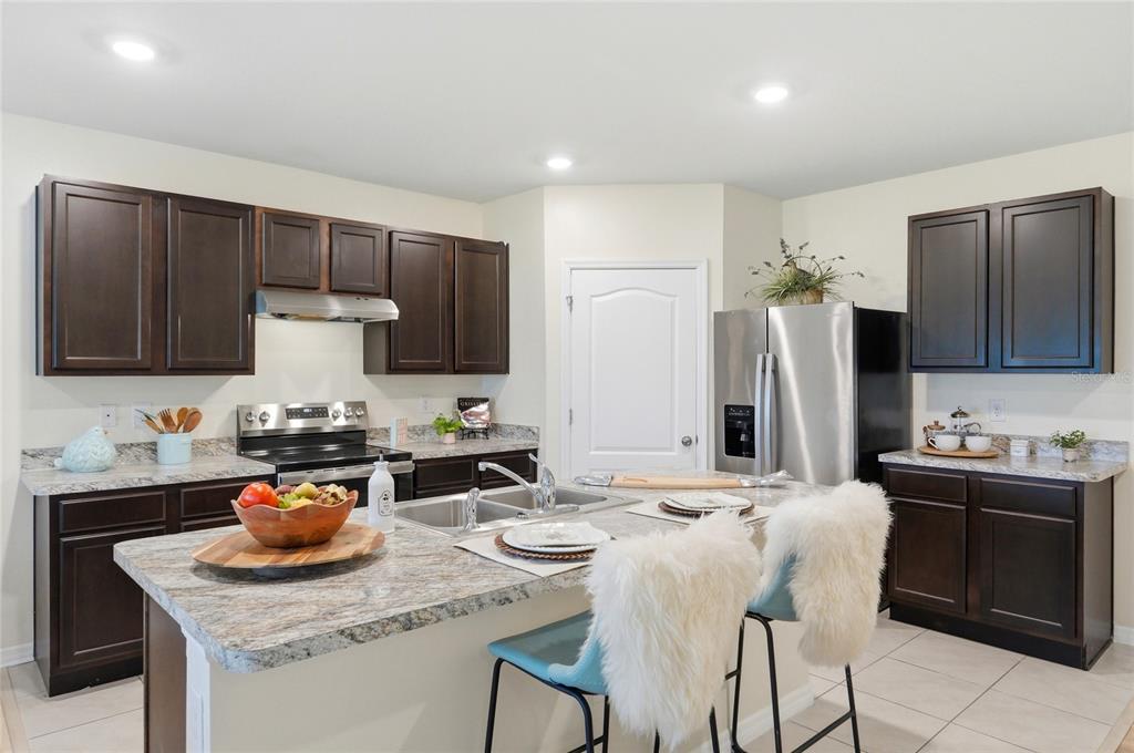 416 Corso Loop Winter Haven, FL 33884 - Photo 16 of 73 a kitchen with stainless steel appliances kitchen island granite countertop a sink stove and refrigerator