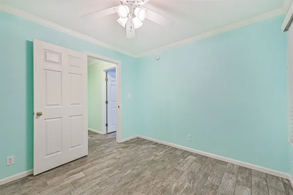 an empty room with a chandelier fan and view of wooden floor