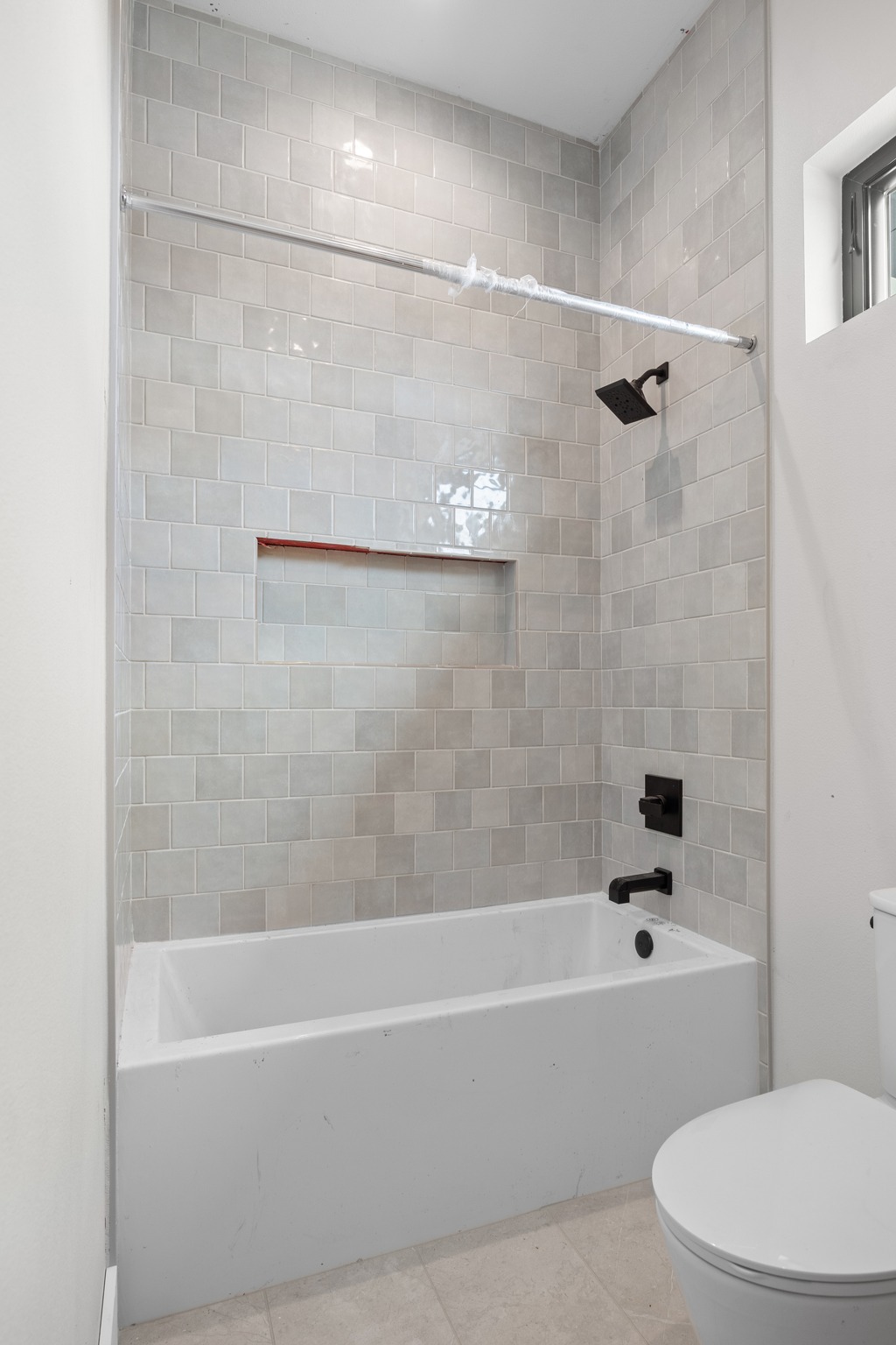 903 Flint Ridge Trail Georgetown, TX 78628 - Photo 31 of 39 Bathtub with light gray subway tile surround featuring a recessed niche, matte black shower head, and matching faucet