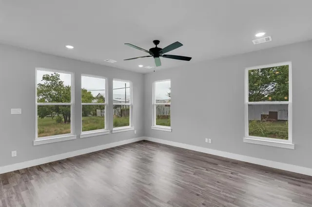 a view of an empty room with a window and wooden floor