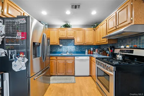 a kitchen with stainless steel appliances granite countertop a refrigerator a stove and a sink