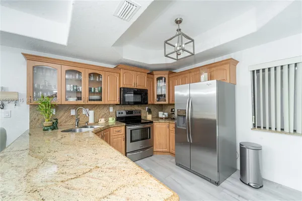 a kitchen with stainless steel appliances granite countertop a refrigerator a stove top oven a sink dishwasher a dining table and chairs with wooden floor