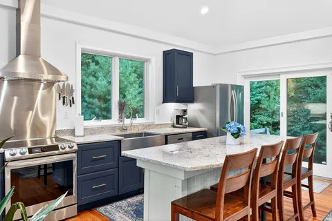 a kitchen with stainless steel appliances granite countertop a stove a refrigerator white cabinets and wooden floor