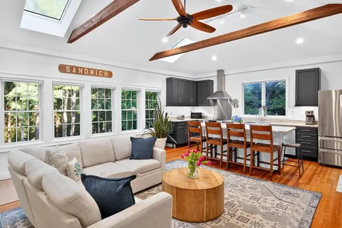 a living room with furniture kitchen view and a large window