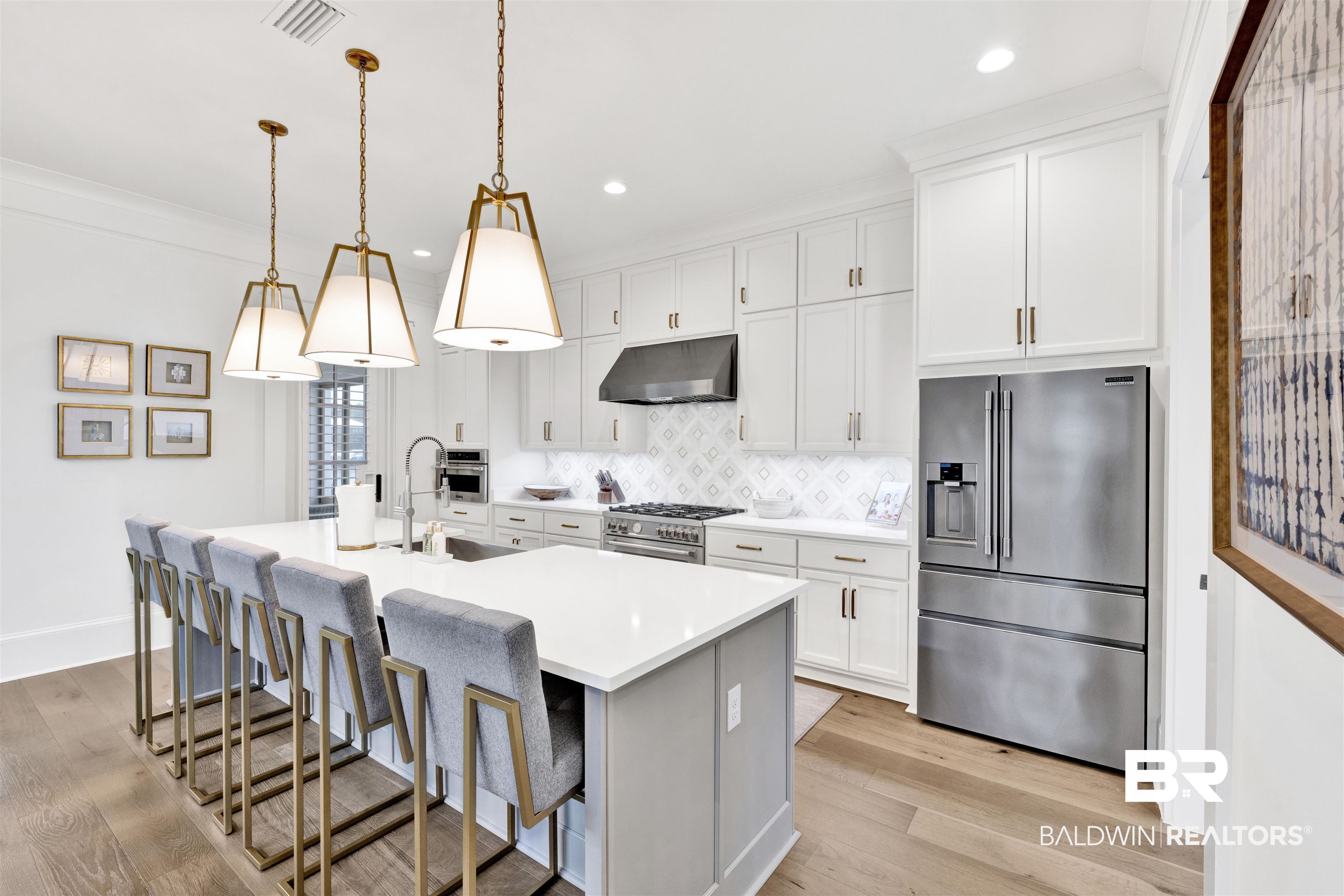 861 Inlet Circle Gulf Shores, AL 36542 - Photo 5 of 54 Kitchen featuring stainless steel appliances, a kitchen bar, a center island with sink, white cabinetry, and ornamental molding