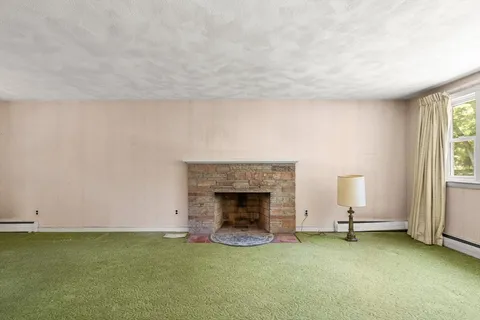 a view of an empty room with window and fireplace
