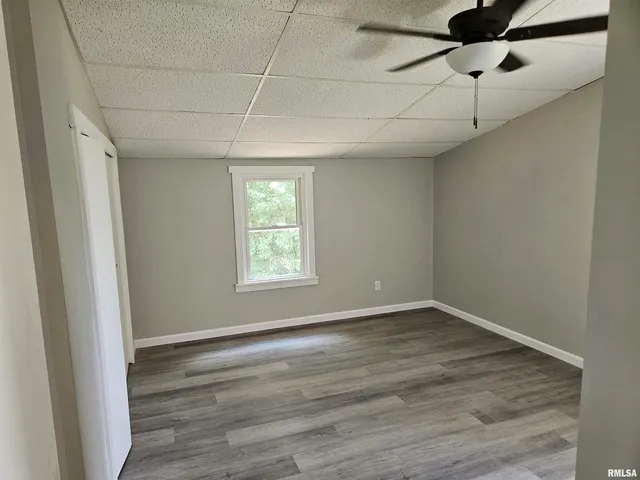 a view of an empty room with a window and wooden floor