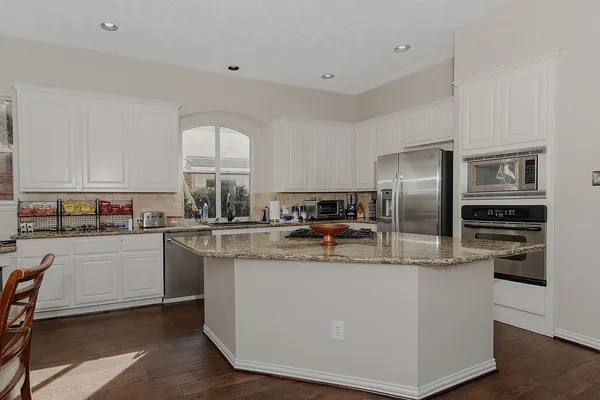a kitchen with stainless steel appliances granite countertop a refrigerator a stove a sink and a refrigerator