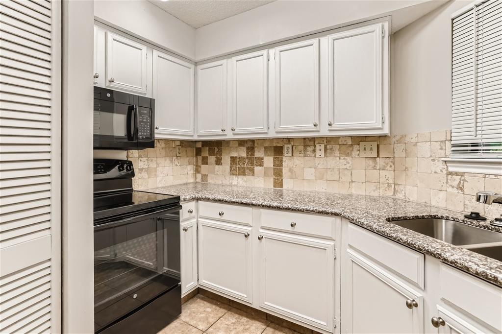 16301 Ledgemont Lane, Unit 269 Addison, TX 75001 - Photo 4 of 22 a kitchen with granite countertop white cabinets and stainless steel appliances