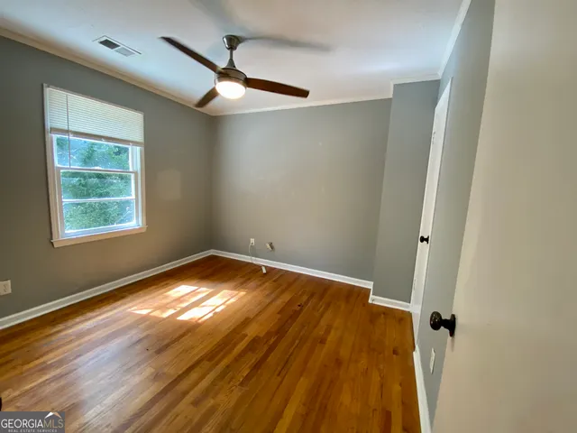 a view of empty room with wooden floor and fan