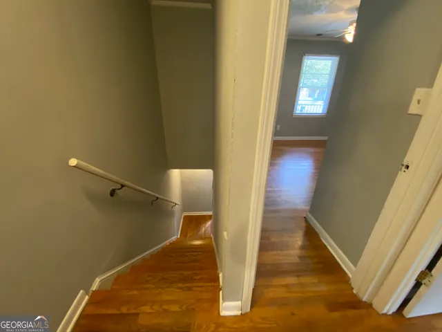 a view of a hallway with wooden floor and staircase