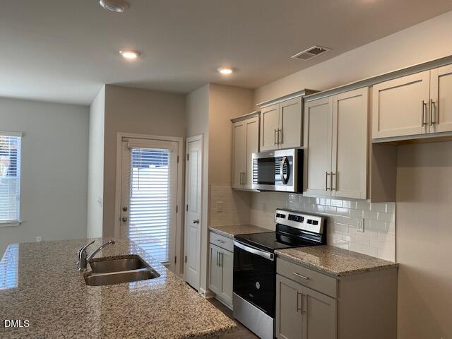 1278 Adrian Court Mebane, NC 27302 - Photo 17 of 33 a kitchen with granite countertop a stove a sink and a refrigerator