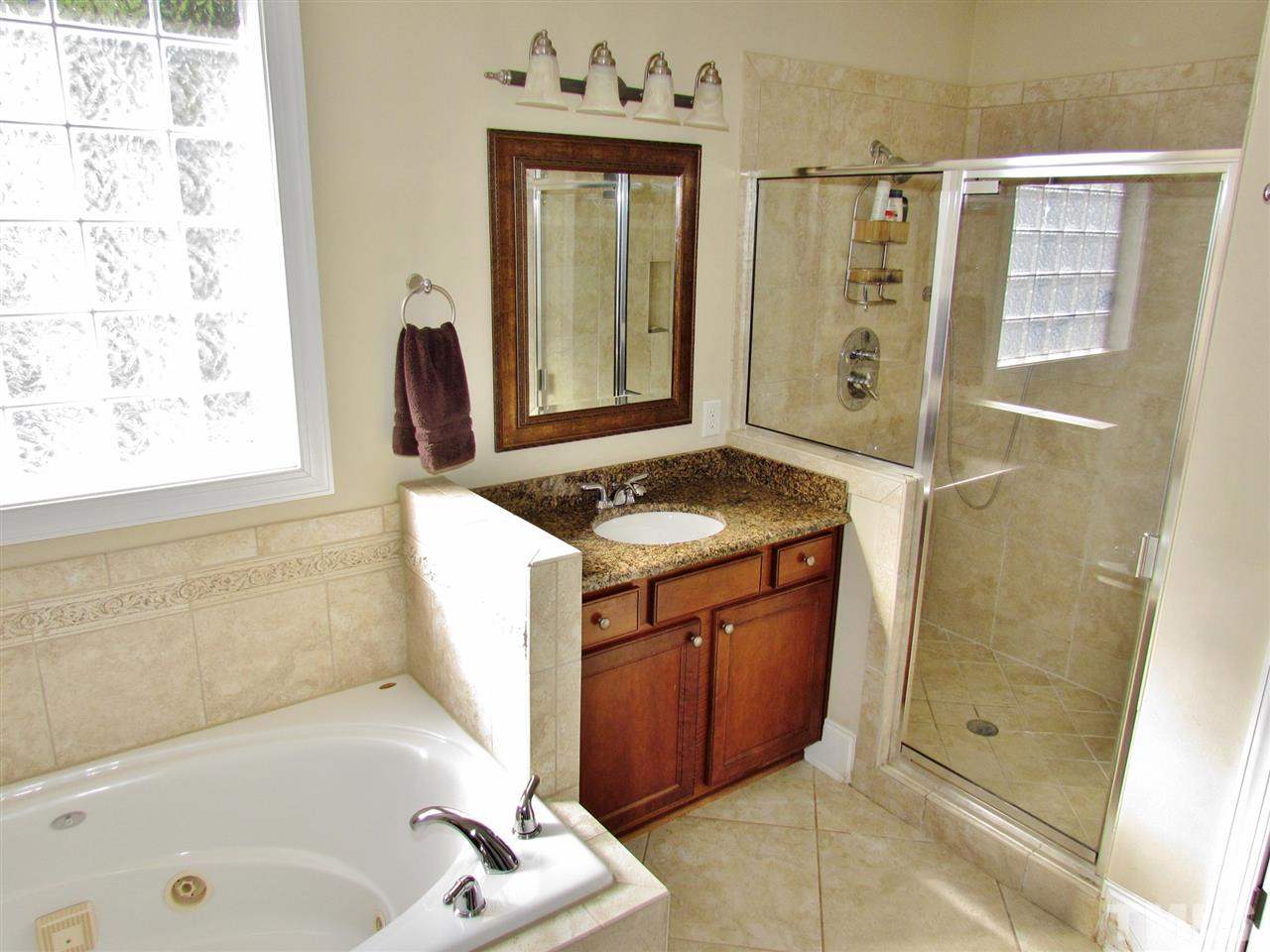 3810 Congeniality Way Raleigh, NC 27613 - Photo 14 of 25 Plenty of room to get ready to start the day or prep for an evening out. There is another vanity on the other side so everyone has plenty of space! Deep whirlpool tub offers a spot to relax and unwind. The oversize tiled shower is spacious.
