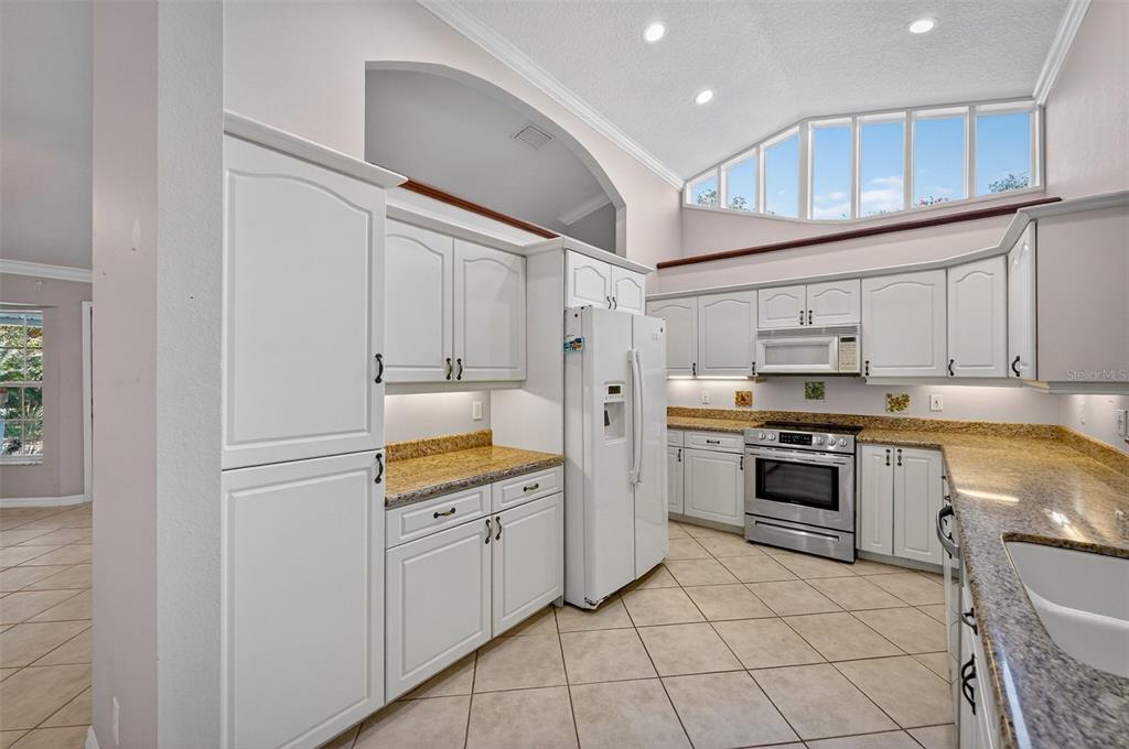 4875 Sailfish Drive Ponce Inlet, FL 32127 - Photo 16 of 60 a kitchen with white cabinets and white appliances