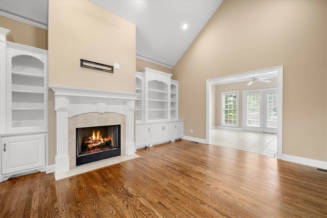 128 Cayman Way Anderson, SC 29621 - Photo 7 of 49 This living area features a warm fireplace, rich hardwood floors, and elegant built-in shelving. virtual fire