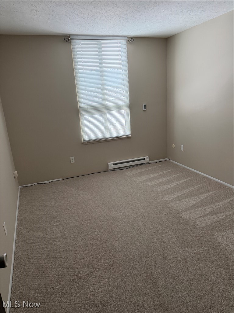 3066 Kent Road, Unit 407 Stow, OH 44224 - Photo 8 of 16 Spare room featuring a textured ceiling, carpet, and a baseboard heating unit