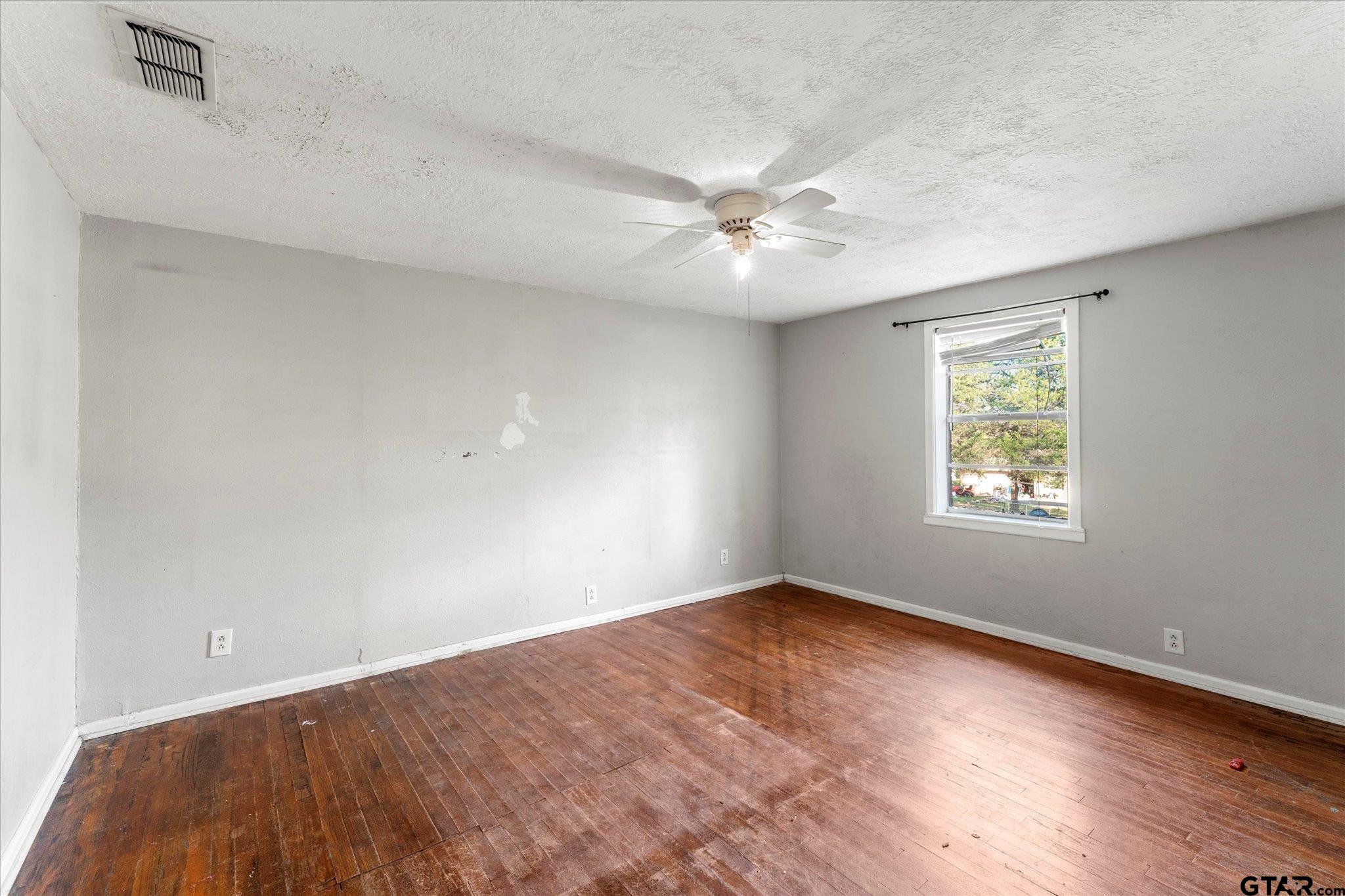 1108 Merritt Avenue Mount Pleasant, TX 75455 - Photo 13 of 17 an empty room with wooden floor ceiling fan and windows