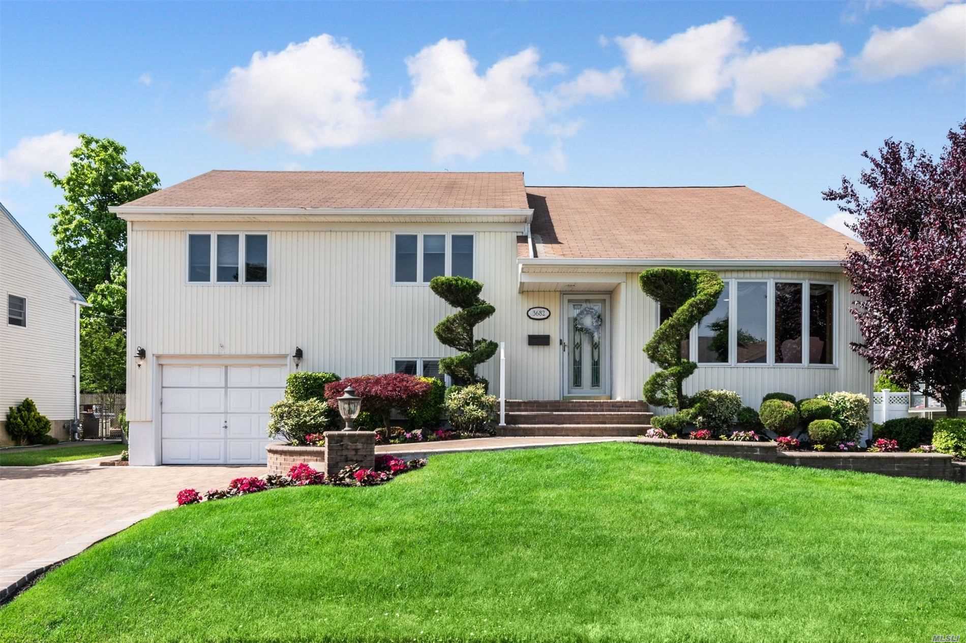a front view of a house with a garden and plants