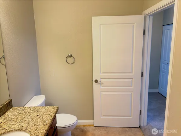 a bathroom with a granite countertop toilet and a sink