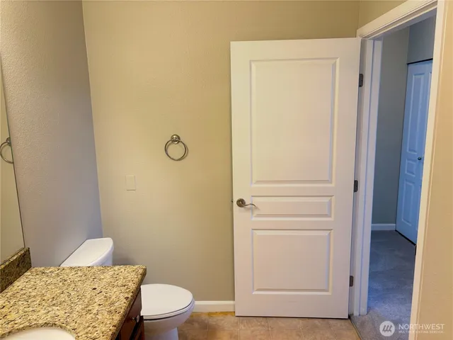 a bathroom with a granite countertop toilet and a sink