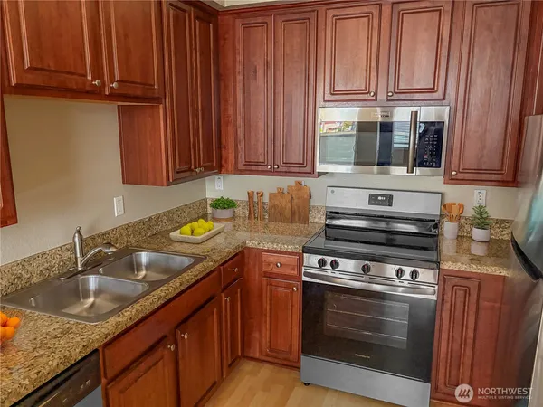 a kitchen with stainless steel appliances granite countertop a sink stove and cabinets