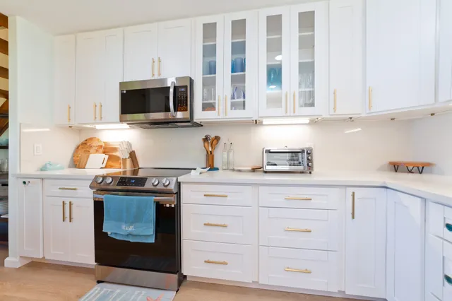 a kitchen with stainless steel appliances granite countertop white cabinets and a stove