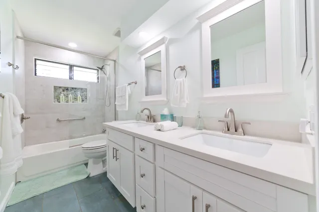 a bathroom with a double vanity sink toilet mirror and bathtub
