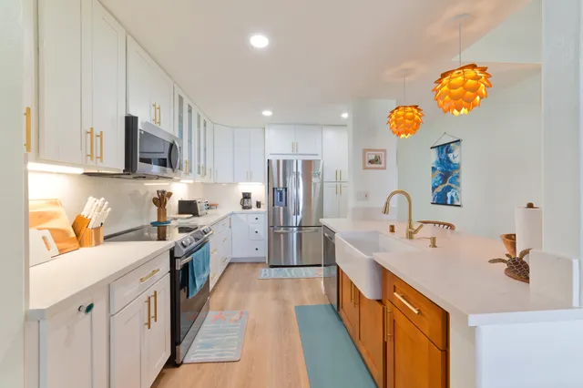 a kitchen with kitchen island granite countertop a sink a counter top space stainless steel appliances and cabinets