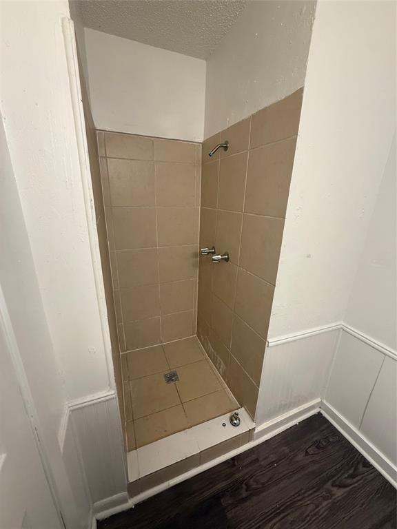 708 East Pecan Street, Unit 712 Hurst, TX 76053 - Photo 14 of 15 Master Bathroom featuring a black vanity with a white-veined countertop, white cabinetry, a built-in mirror, and wood-finish flooring