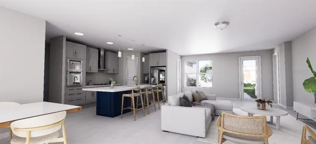 a living room with stainless steel appliances kitchen island granite countertop a table chairs and a refrigerator