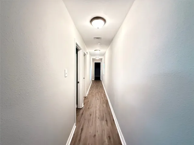 a view of a hallway with wooden floor and staircase