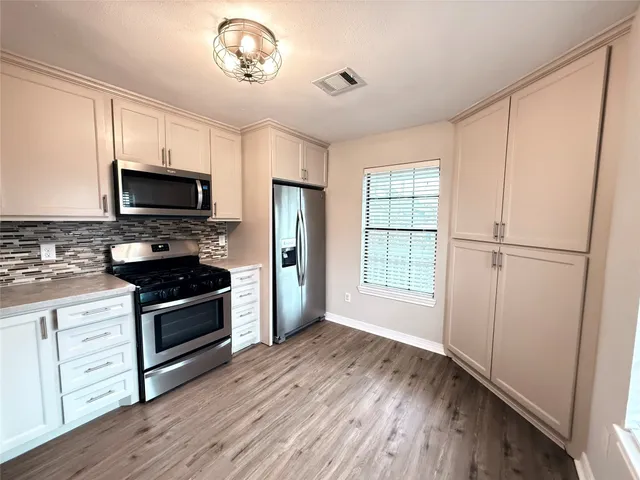 a kitchen with granite countertop a stove a sink and a refrigerator