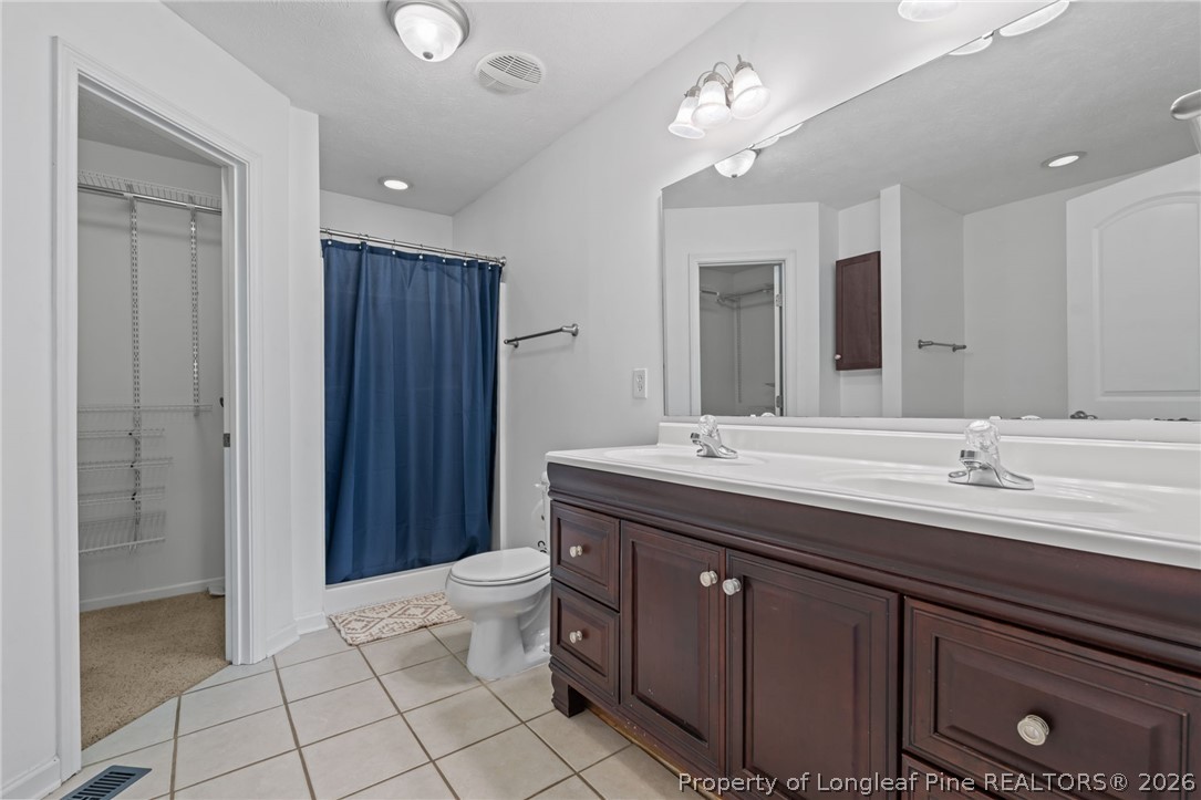 115 Shelby Street Spring Lake, NC 28390 - Photo 24 of 40 a bathroom with a double vanity sink a toilet and a mirror