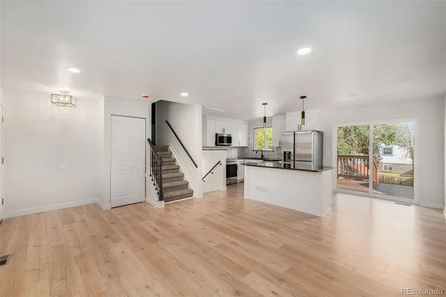 a view of a living room a kitchen with wooden floor and stairs