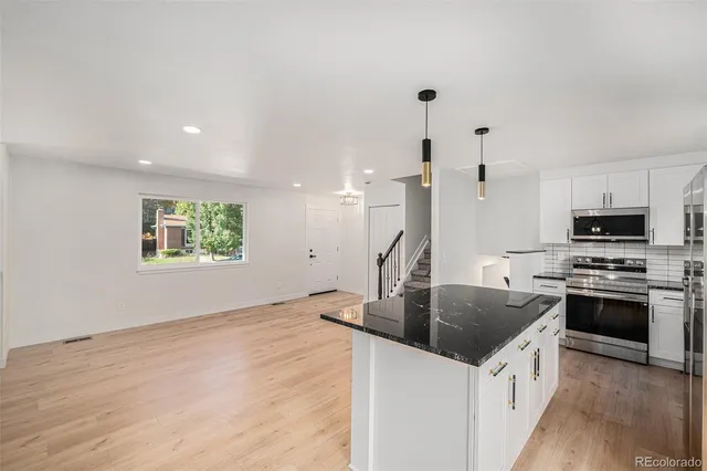 a kitchen with stainless steel appliances granite countertop a sink a stove and a refrigerator